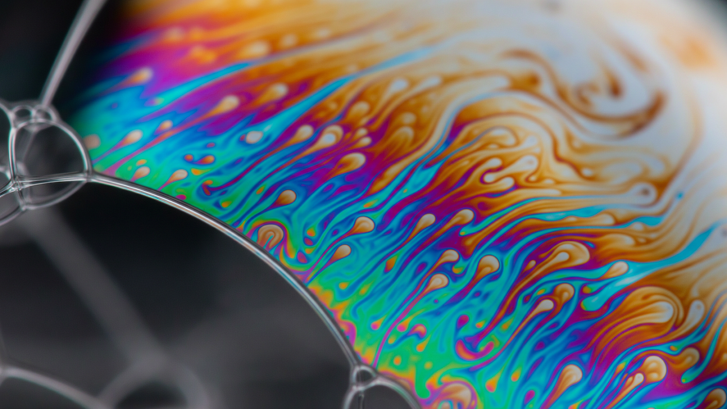 AI-generated image of: extreme close-up of a soap bubble surface, displaying swirling, liquid patterns of iridescent rainbow colors that look like flowing oil on a thin, glossy film